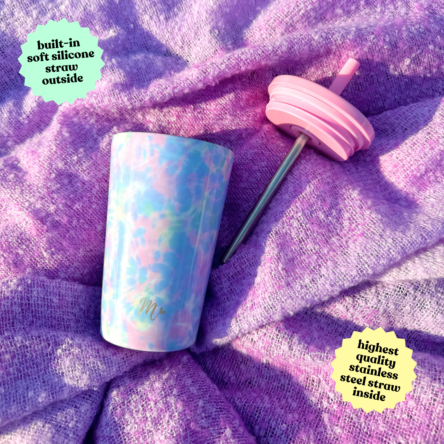 Pastel tie-dye 14 oz stainless steel cup placed on a purple textured fabric, with the lid and stainless steel straw set beside it, highlighting the built-in soft silicone straw and high-quality stainless steel straw inside.