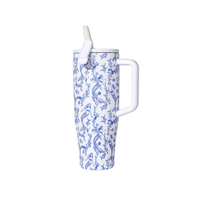 White mug with blue mermaid pattern and straw on a white background