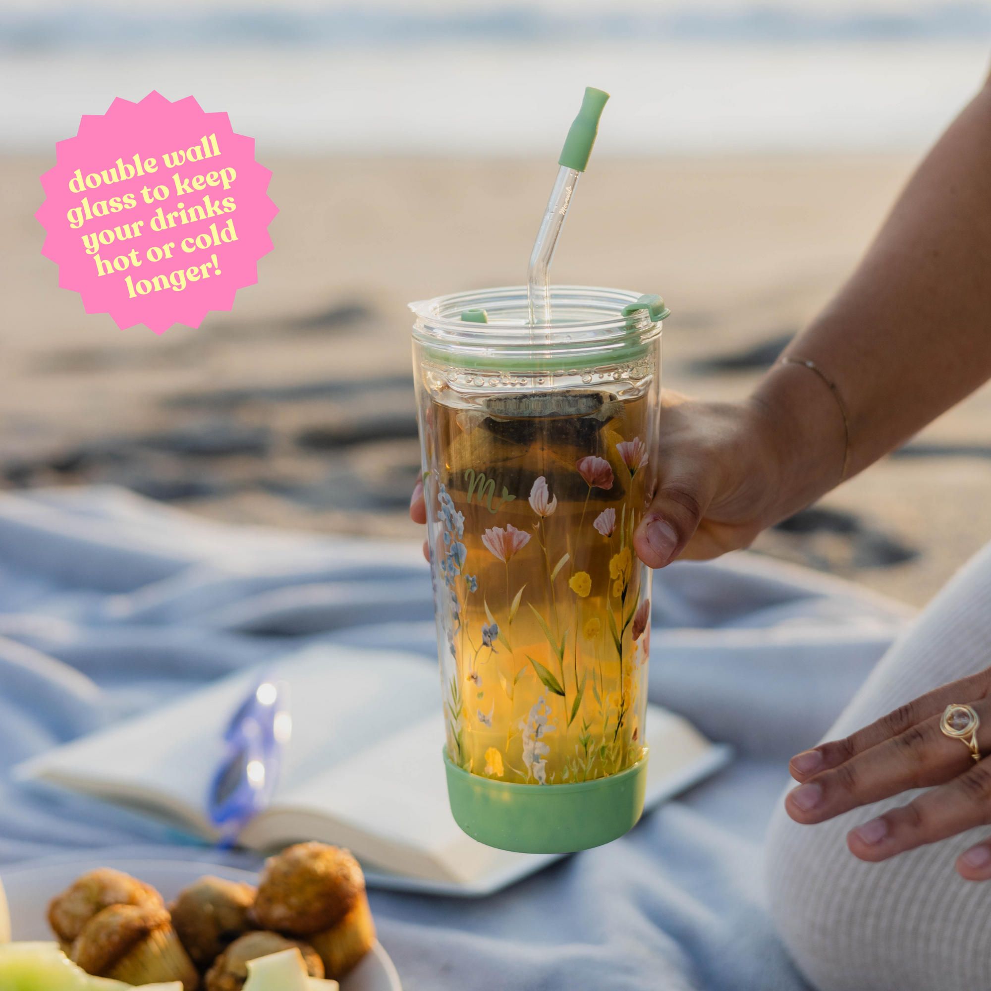 Hand holding a 20oz wildflower-designed double-wall glass cup with text: 'Double wall glass to keep your drinks hot or cold longer!